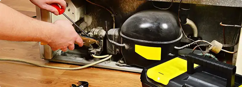 Refrigerator repair technician fixing the compressor and wiring in Carteret, NJ