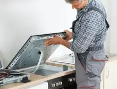 Appliance repair technician installing a built-in cooktop in Staten Island, NY