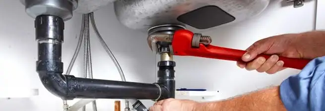 Garbage disposal repair technician tightening the sink drain and disposal connection in Staten Island, NY