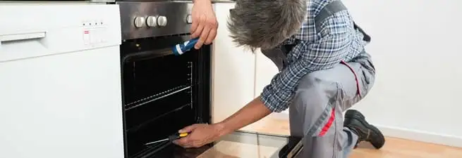 Oven repair technician inspecting and servicing an electric oven in Staten Island, NY