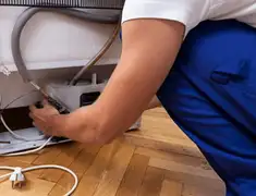 Appliance repair technician fixing refrigerator water line and connections in Staten Island, NY