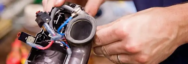 Vacuum repair technician reconnecting wiring and components in Staten Island, NY