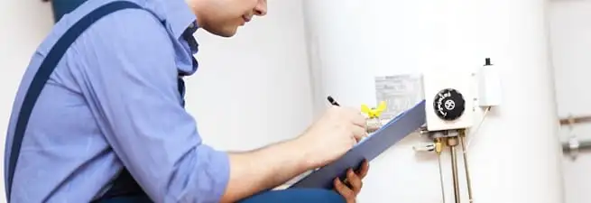 Water heater repair technician inspecting the unit and recording service notes in Staten Island, NY