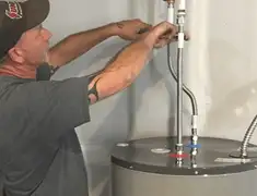 Water heater repair technician tightening supply line connections in Staten Island, NY