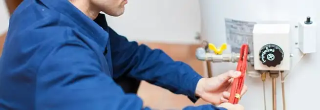 Water heater repair technician adjusting the temperature control and gas valve in Staten Island, NY